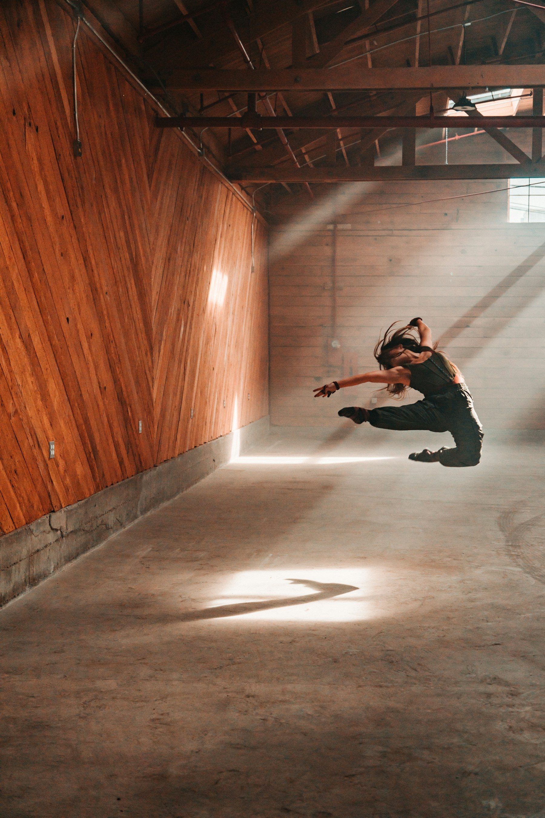 A dancer mid-leap in a warehouse studio